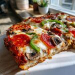 Close-up of a thick-crust pizza slice featuring pepperoni, mushrooms, and green peppers, highlighting the Best Pizza Toppings.