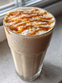 A tall glass of creamy Coconut Caramel Smoothie topped with a rich caramel drizzle.