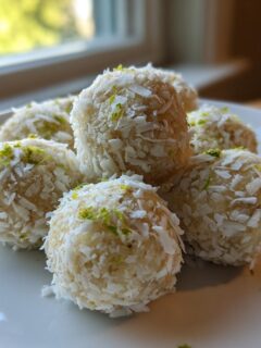A stack of homemade Coconut Lime Energy Balls rolled in shredded coconut and topped with lime zest.