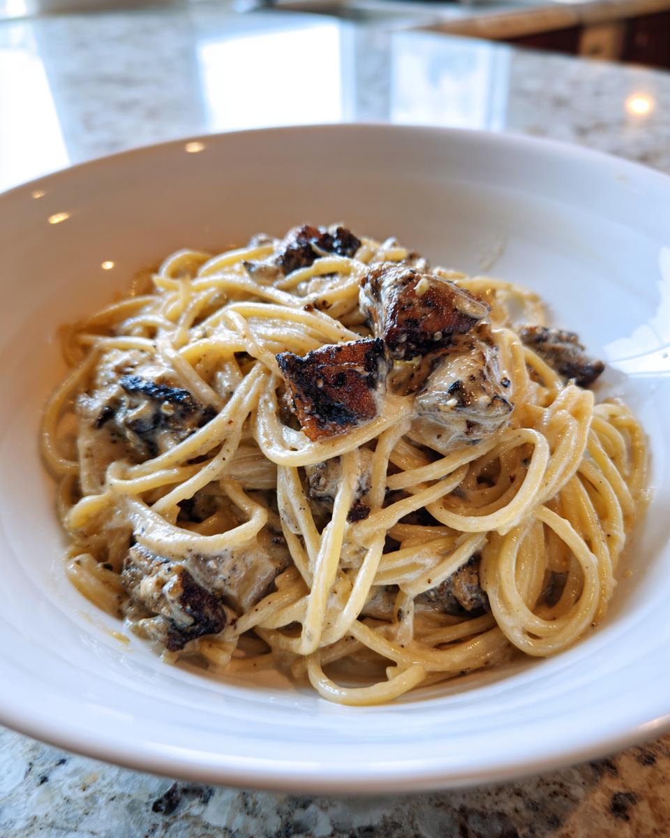 Close-up of creamy Jerk Chicken Alfredo Pasta with perfectly coated spaghetti and charred jerk chicken pieces.