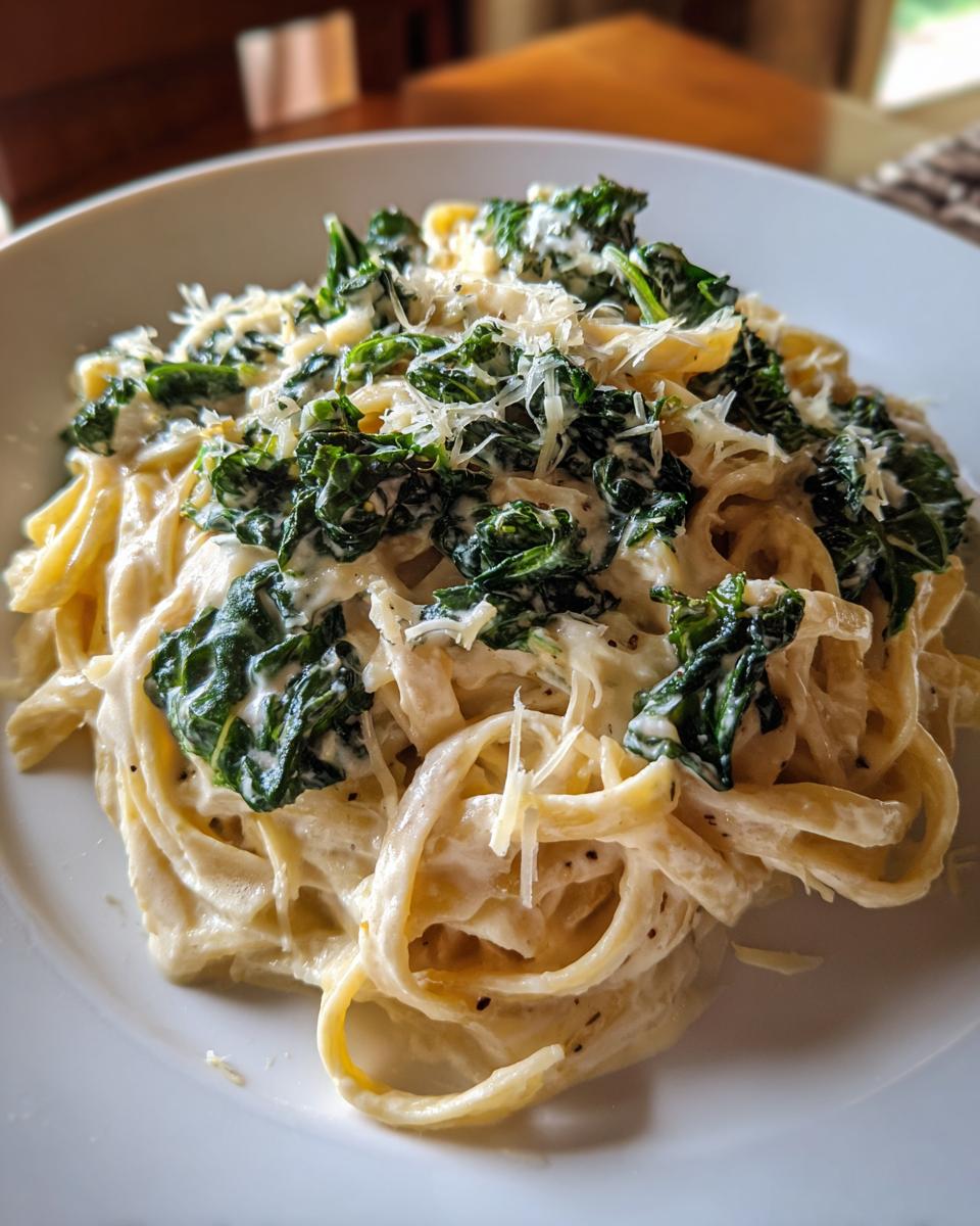 A close-up of Creamy Roasted Garlic Kale Pasta With Parmesan topped with shredded cheese.