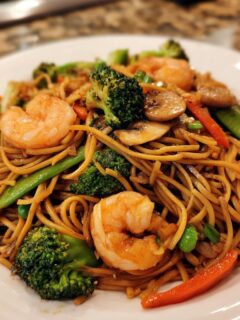 Close-up of a plate of Healthy Shrimp Lo Mein with shrimp, broccoli, mushrooms, and noodles.