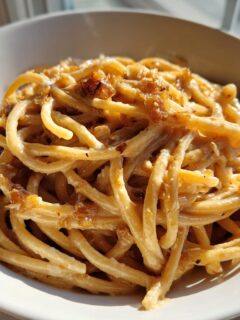 Close-up of creamy Date Night Roasted Garlic Parmesan Bucatini pasta served in a white bowl.