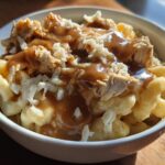 Close-up of an Easy KFC Mac Cheese Bowl Copycat featuring macaroni, shredded chicken, brown gravy, and white cheese shreds.