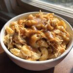 Close-up of an Easy KFC Mac Cheese Bowl Copycat featuring macaroni, shredded chicken, and brown gravy.