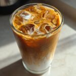 Close-up of an Easy Pumpkin Pie Iced Latte with ice cubes and milk swirling into the coffee.