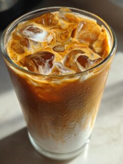Close-up of an Easy Pumpkin Pie Iced Latte with ice cubes and milk swirling into the coffee.