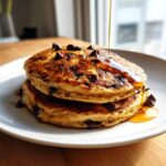 A stack of two fluffy Easy Vegan Chocolate Chip Pancakes being drizzled with syrup.