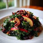 A vibrant serving of Fall Harvest Apple Kale Salad topped with pecans, dried cranberries, and fresh apple slices.