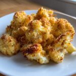 Close-up of crispy, golden brown Garlic Parmesan Roasted Cauliflower florets piled on a white plate.