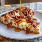 A slice of Gluten Free Hot Honey Bacon Pizza being drizzled with hot honey on a white plate.