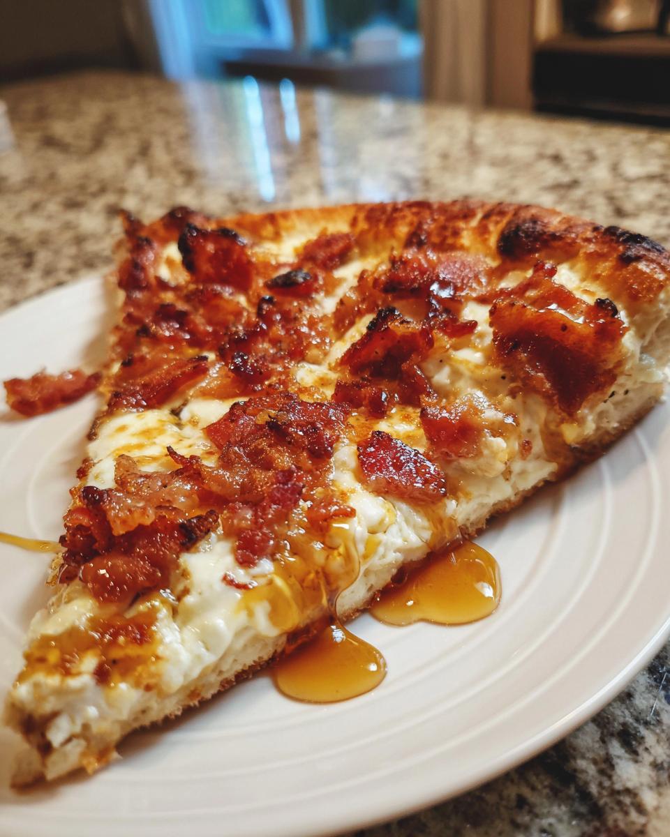 Close-up of a slice of Gluten Free Hot Honey Bacon Pizza, drizzled with honey, sitting on a white plate.