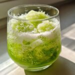Close-up of a vibrant green, bubbly Halloween Witches Brew Mocktail topped with bright green slushy ice.