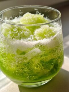 Close-up of a vibrant green, bubbly Halloween Witches Brew Mocktail topped with bright green slushy ice.