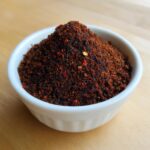 A close-up of a mound of dark, rich Homemade Blackened Seasoning piled high in a small white bowl.