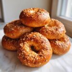 A stack of freshly baked Homemade Pumpkin Oat Bagels topped generously with oats and spices.
