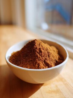 A small white bowl filled with a mound of freshly mixed Homemade Pumpkin Pie Spice Blend.
