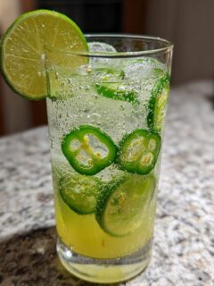Close-up of a fizzy Jalapeno Lemon Lime Mocktail garnished with a lime wheel and filled with jalapeno slices.