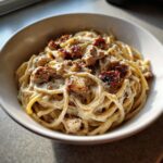 Close-up of a bowl of creamy Jerk Chicken Alfredo Pasta topped with seasoned chicken pieces.