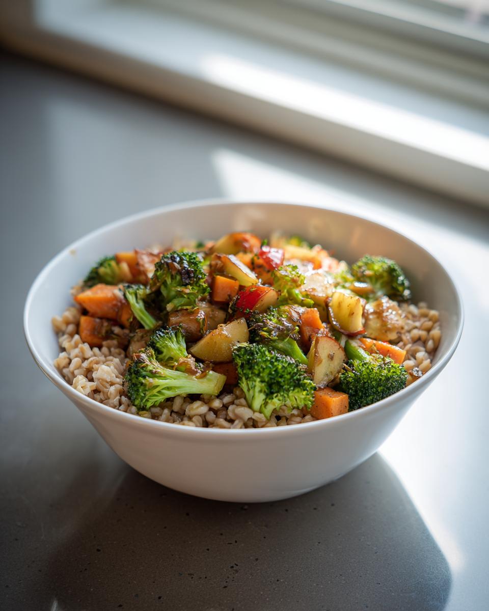 Close-up of a Jerk Vegetable Farro Bowl featuring farro, broccoli, sweet potatoes, and apples in a white bowl.