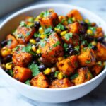 Close-up of roasted sweet potato cubes mixed with black beans, corn, and cilantro in a white bowl, ready for the Maple Chili Sweet Potato Bowl.