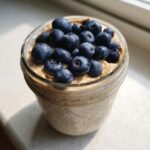 Close-up of Maple Cinnamon Overnight Oats in a mason jar, topped generously with fresh blueberries.