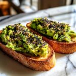 Two slices of Mind Blowing Avocado Toast topped with mashed avocado and everything bagel seasoning.