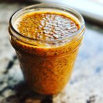 A close-up, vibrant photo of Pumpkin Pie Chia Pudding textured with soaked chia seeds in a clear glass jar.