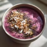 Close-up of a vibrant Raspberry Coconut Smoothie Bowl topped with chia seeds, toasted coconut flakes, and granola.