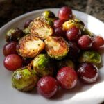 A close-up of caramelized Roasted Brussels Sprouts Grapes mixture served on a white plate.