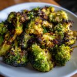 Close-up of vibrant green Roasted Garlic Parmesan Broccoli with crispy, browned edges served on a white plate.