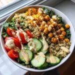 A vibrant Savory Chickpea Quinoa Buddha Bowl featuring quinoa, spiced chickpeas, tomatoes, cucumbers, and a creamy drizzle.