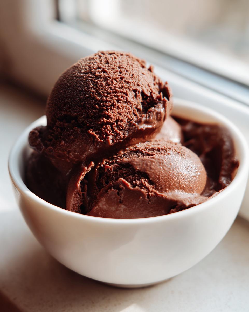 Three scoops of rich, dark Vegan Chocolate Avocado Pudding served in a white bowl.
