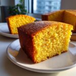 Close-up of a moist, golden slice of Vegan Sweet Cornbread on a white plate.