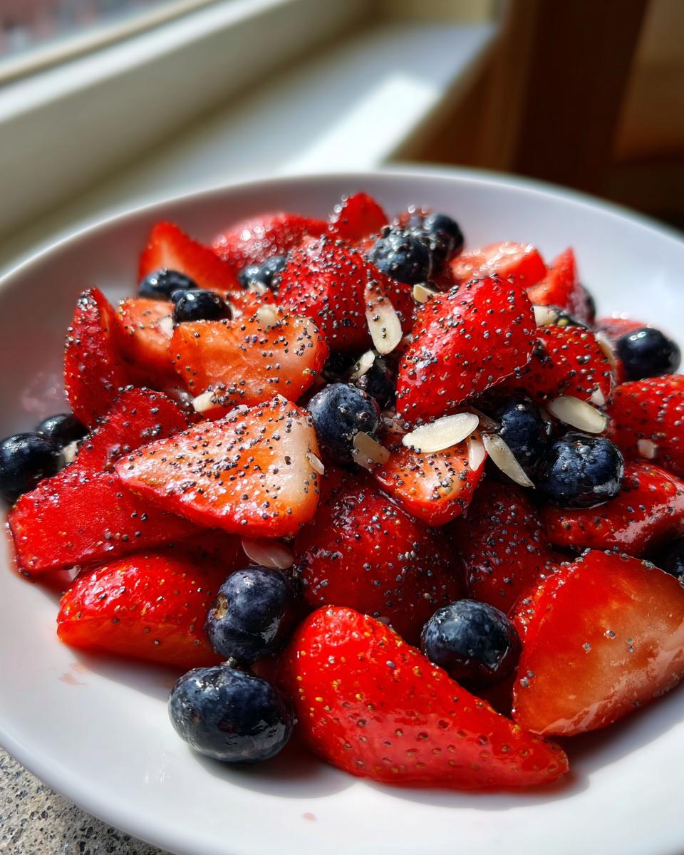 Close-up of sliced strawberries and blueberries tossed with poppy seeds and slivered almonds, perfect for 4th Of July Strawberries.