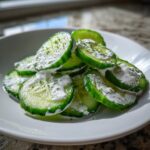 Close-up of sliced cucumbers topped with creamy ranch dressing and green seasoning, perfect 5 Minute Cucumber Snack With Ranch Flavors.