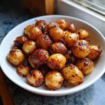 A white bowl filled with perfectly caramelized and slightly charred Air Fryer Pearl Onions, ready to serve.