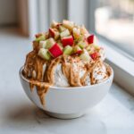 A close-up of an Apple Peanut Butter Yogurt Bowl topped with diced red and green apples and drizzled peanut butter.