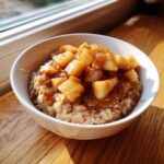 Close-up of a warm Apple Pie Breakfast Bowl topped with caramelized cinnamon apples.