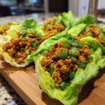 Close-up of several Asian Lettuce Wraps filled with savory ground meat mixture and topped with green onions.