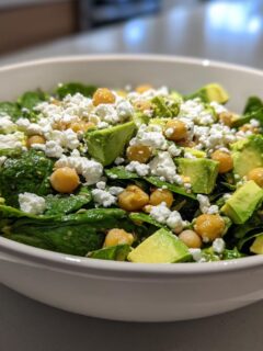 Close-up of a vibrant Avocado Feta Chickpea Bowl featuring spinach, avocado chunks, chickpeas, and crumbled feta.