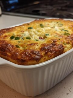 A golden-brown, baked Jalapeno Popper Dip served hot in a white, ribbed baking dish.