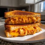 Close-up of a perfectly grilled BBQ Chicken Grilled Cheese sandwich, cut in half, showing melted cheese and shredded chicken.