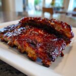 Close-up of tender BBQ Honey Garlic Ribs coated in a thick, glossy, dark red glaze.