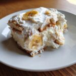 A generous serving of the Best Banana Pudding layered with vanilla wafers, cream, and topped with fresh banana slices.