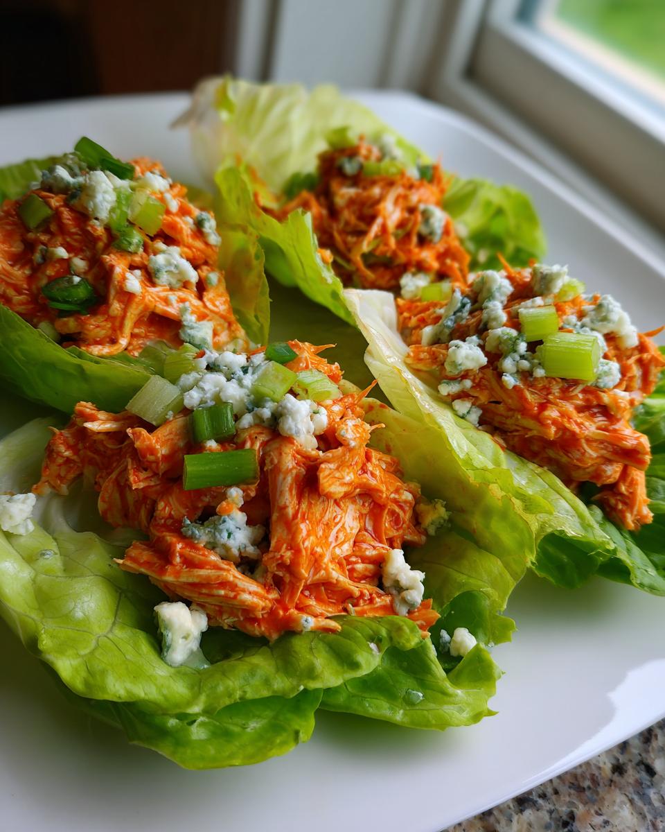 Three servings of Buffalo Chicken Lettuce Boats filled with orange shredded chicken, blue cheese crumbles, and green onions.