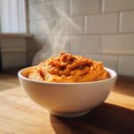 A bowl of hot, steaming Butternut Squash Dip With Air Fryer Roasted Garlic topped with spices.