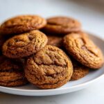 A close-up of several chewy Chai Spiced Apple Butter Cookies rolled in sugar on a white plate.
