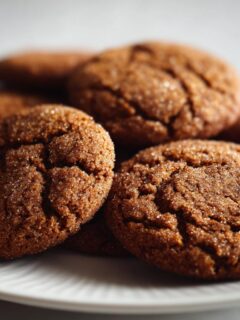 Close-up of several soft, crackled Chai Spiced Apple Butter Cookies dusted with sugar on a white plate.