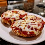 Close-up of two freshly baked Freezer Bagel Pizzas topped with melted, bubbly mozzarella cheese on a white plate.